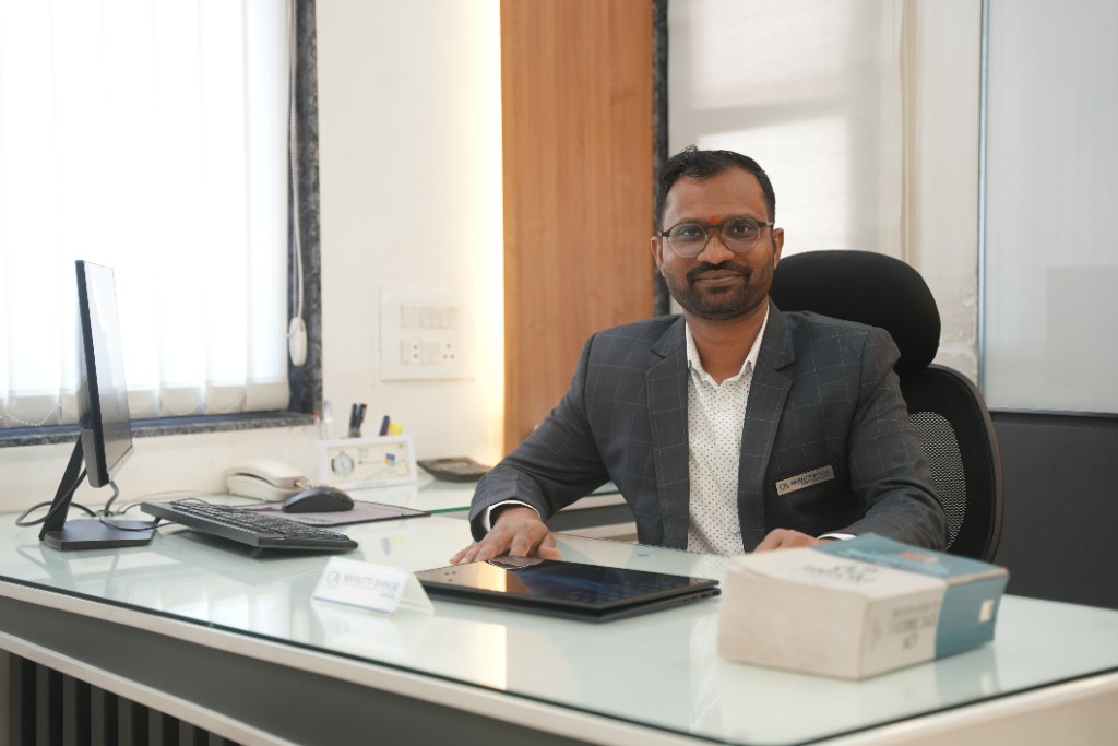 CA Nivrutti Shinde seated at his office desk in a modern workspace