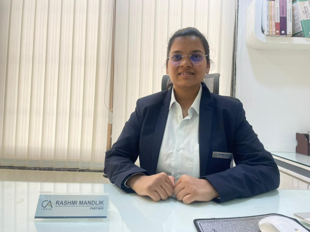 CA Rashmi Mandlik, Partner, seated at her office desk with tax and reference books in the background
