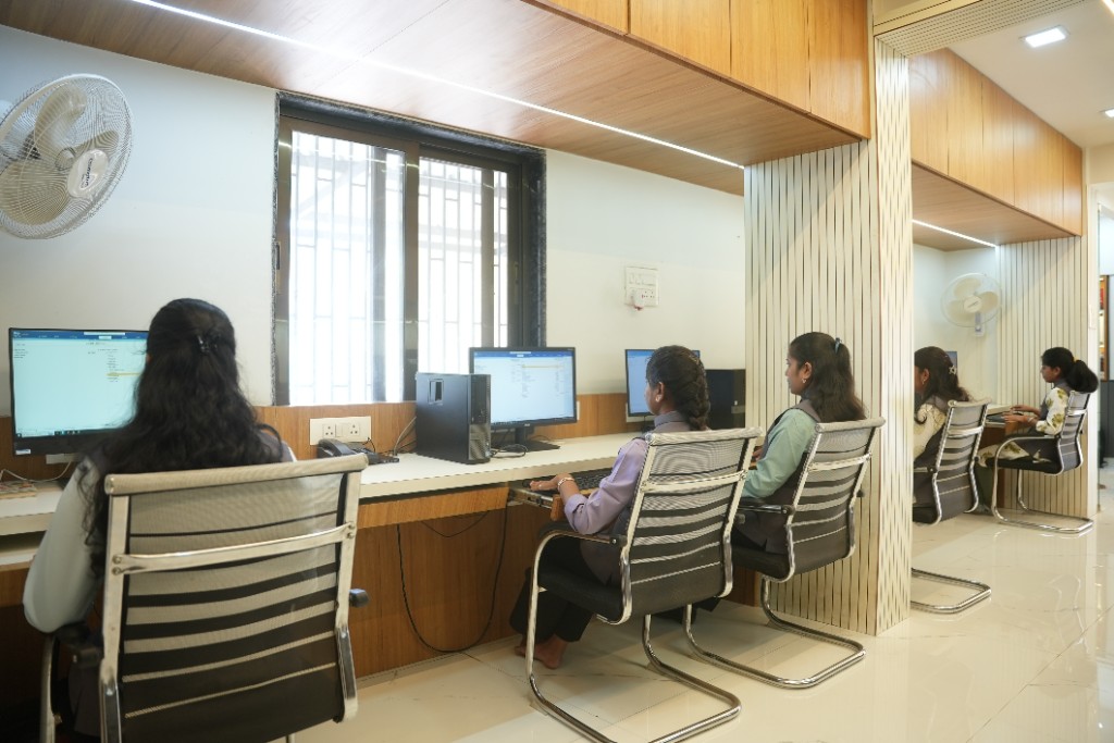 Staff members working at modern computer workstations along a bright, professional office desk