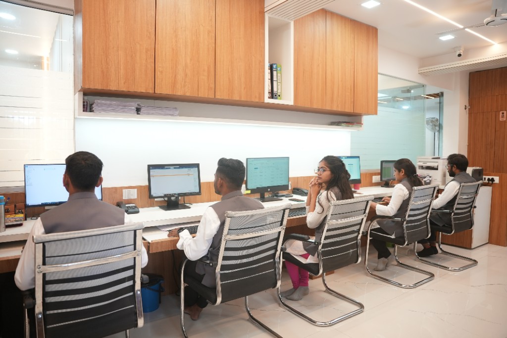 Team of accountants working at a long shared desk with computers in a bright, modern office at SKMRD & Associates